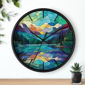 May include: A black framed clock with a stained glass design of a mountain lake scene. The design features a blue lake with a reflection of the mountains, a green forest, and a blue sky with yellow clouds.