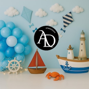 May include: A nautical-themed display featuring a toy sailboat with a red sail, a toy boat with a lighthouse, and a plush orange crab. Blue balloons, kites, and clouds decorate the background. The logo "ATDSCRAFT" is in a black circle.