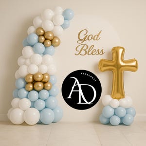 Pode incluir: Um arco de balões em branco, azul claro e dourado, com um balão de cruz dourada e as palavras "God Bless". Também está presente um círculo preto com texto branco. Ideal para um batismo ou primeira comunhão.