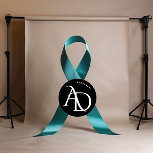 May include: A teal blue ribbon tied in a bow with the text "ATDSCRAFT" and the letters "AD" in a black circle in the center.