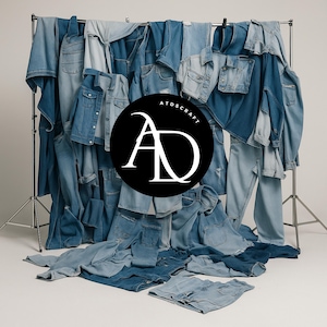 Puede incluir: Exhibición de varias prendas de mezclilla, incluyendo chaquetas y jeans, en tonos azules. Los artículos están dispuestos en un estante metálico contra un fondo blanco. Un círculo negro con el texto blanco "ATOSCRAFT" y el logotipo estilizado "AD" es visible.