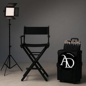 May include: A black director's chair, a rolling makeup case with brushes, and a studio light on a tripod stand. The makeup case has a logo that says "ATOSCRAFT" and "AD".