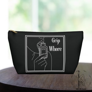 Könnte beinhalten: Schwarze Reißverschlusstasche mit einer weißen Umrandung einer Person, die eine Flasche an die Lippen hält. Der Text "Grip Whore" ist in Weiß gedruckt.