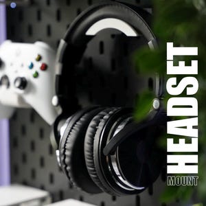 May include: Black over-ear headphones with a silver accent on the earcups are hanging on a pegboard wall. The text "HEADSET MOUNT" is visible in the image.