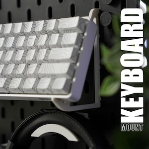 May include: A white keyboard with a patterned design is mounted on a black pegboard wall. The keyboard is mounted on a white bracket. The text "KEYBOARD MOUNT" is visible in the image.