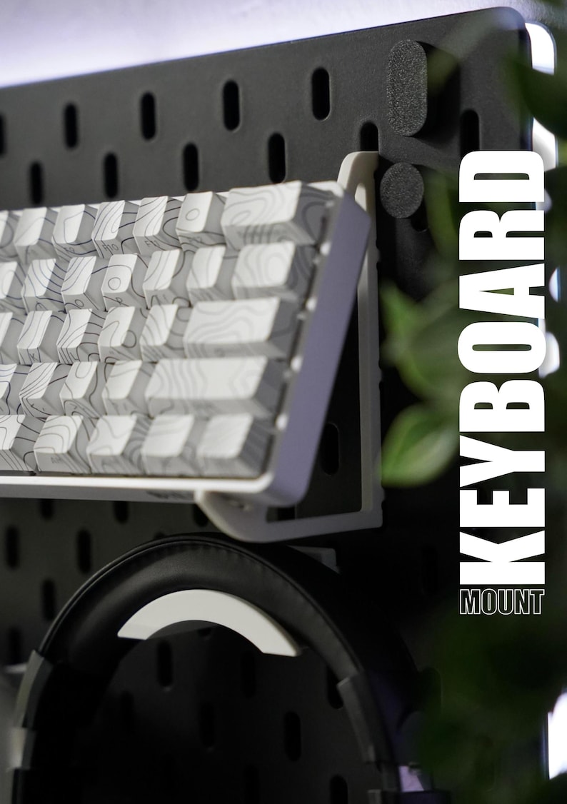 May include: A white keyboard with a patterned design is mounted on a black pegboard wall. The keyboard is mounted on a white bracket. The text "KEYBOARD MOUNT" is visible in the image.
