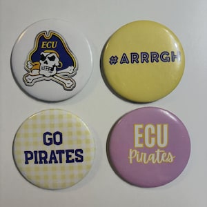 Puede incluir: Cuatro chapas redondas con alfiler. La superior izquierda es blanca con un logo de calavera pirata ECU. La superior derecha es amarilla con el texto #ARRRGH en morado. La inferior izquierda tiene un patrón de cuadros vichy amarillo con el texto GO PIRATES. La inferior derecha es lavanda con el texto ECU Pirates en amarillo y blanco.