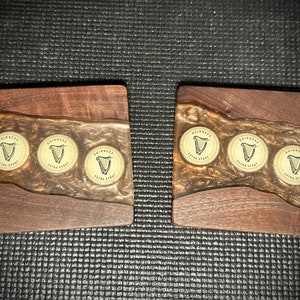 Pu&ograve; includere: Tre sottobicchieri in legno con un top in resina epossidica trasparente. Ogni sottobicchiere presenta tre tappi di bottiglia Guinness Extra Stout incorporati nella resina.