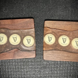 Pu&ograve; includere: Due sottobicchieri in legno con una macchia marrone e una parte superiore in resina epossidica trasparente. Ogni sottobicchiere ha tre tappi di bottiglia Guinness Extra Stout incorporati nella resina.