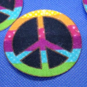 Könnte beinhalten: Ein farbenfroher Friedenszeichen-Stoffpatch mit einem Regenbogenmuster. Der Patch hat einen Durchmesser von etwa 1 Zoll.