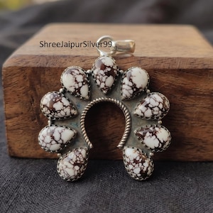 May include: A silver pendant featuring a horseshoe-shaped frame adorned with nine teardrop-shaped white stones with dark brown spiderweb veining. The metal border has a twisted rope texture. The text ShreeJaipurSilver99 is visible at the top.