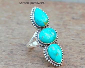 Peut inclure: Une bague en argent sterling ornée de trois pierres de turquoise serties en chaton disposées verticalement. Les pierres du haut et du bas sont en forme de poire, tandis que la pierre centrale est ovale. Chaque pierre est bordée de perles.