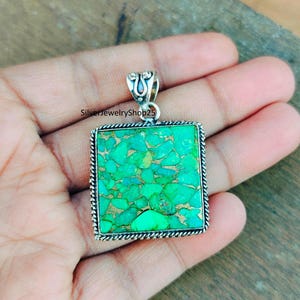 May include: A silver pendant with a square turquoise stone. The stone is a mosaic of green and blue turquoise pieces.