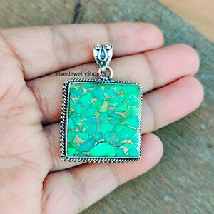 May include: A square turquoise pendant with a silver frame and a silver bail. The turquoise is a green and blue color with a marbled pattern.