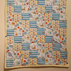 May include: A Winnie the Pooh themed patchwork quilt with a yellow border. The quilt is made up of various squares with different patterns featuring Winnie the Pooh, Tigger, Piglet, and Eeyore characters, balloons, and stripes.