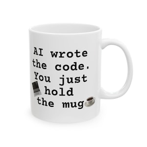 Op de afbeelding: Witte keramische mok met zwarte tekst: "AI wrote the code. You just hold the mug." Een kleine laptopafbeelding en een koffiekopje staan ook op de mok. De mok heeft een gebogen handvat.