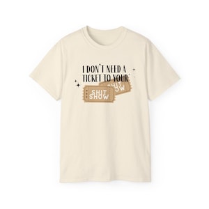 May include: A beige t-shirt with a graphic print of two ticket stubs that say "Shit Show" and the text "I don't need a ticket to your... Shit Show".