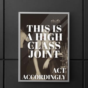 May include: Framed print with a sepia-toned image of a woman in a bar setting. The print features the text "THIS IS A HIGH CLASS JOINT ACT ACCORDINGLY" in bold white letters. The print is displayed on a black wall.