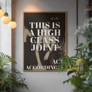 May include: A framed black and white print with the text "THIS IS A HIGH CLASS JOINT ACT ACCORDINGLY". The image features a person in a dress leaning on a bar. The print is in a room with hanging lights and plants.