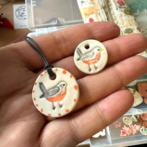 May include: A white ceramic mug with a black handle and the text "But First, Coffee" in a bold, black font. The mug is filled with a dark liquid, likely coffee, and sits on a light-colored surface.