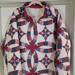 May include: A long-sleeve pullover jacket featuring a quilted construction with a white base and a repeating pattern of red, white, and blue fabric segments. The design includes interlocking circular shapes and star motifs with various polka dot, floral, and plaid prints.
