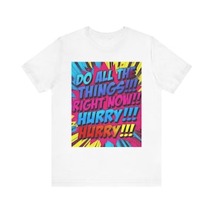 May include: White t-shirt with a colorful comic book style graphic. The graphic reads "DO ALL THE THINGS!!! RIGHT NOW!!! HURRY!!! HURRY!!!" in blue, pink, and yellow text.