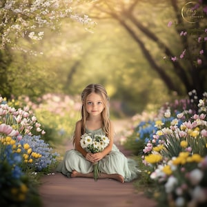 May include: A young girl sits on a path in a flower garden. She is wearing a light green dress and holding a bouquet of white daisies. The path is lined with colorful flowers, including pink, yellow, and blue.