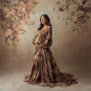 Puede incluir: Una mujer con un vestido largo y fluido de maternidad con un estampado floral en tonos marrones y beige. El vestido tiene mangas largas y un escote en V. El fondo presenta un arreglo floral en tonos similares.