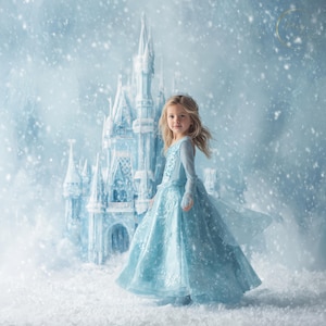May include: A young girl in a light blue gown stands in a snowy scene with a large, icy castle in the background. The dress has long sleeves and intricate detailing. Snowflakes fall around the girl and the castle, creating a winter wonderland atmosphere.