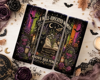 May include: A cylindrical tumbler featuring a dark, mystical design with a black cat, an open book, potion bottles, and tombstones. The text reads A WELL-EDUCATED WOMAN KNOWS HER POWER, RESTING IN PEACE, and STAY MAGICAL, accented by vibrant purple, green, and orange streaks.