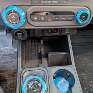 Puede incluir: Consola interior de coche con detalles azules. La imagen muestra el salpicadero con el texto "PASSENGER AIRBAG OFF" y "PRO TRAILER". La palanca de cambios y el portavasos tienen detalles azules. El texto "ENGINE START STOP" es visible.