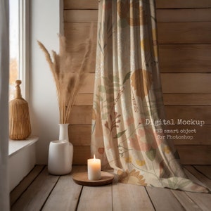 May include: A beige curtain with a floral pattern hangs in a room with wood panelling. A white vase with dried pampas grass sits on a wooden floor next to a lit white candle on a wooden coaster.