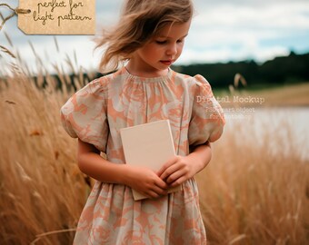May include: A young girl in a peach-colored dress with a floral pattern stands in a field of tall grass. She is holding a blank white book in her hands. The text "perfect for light pattern" is written on a brown tag.