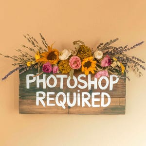 May include: A rustic wooden sign with the text "Photoshop Required" painted in white. The sign is decorated with dried flowers, including sunflowers, lavender, and pink roses.