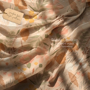 Op de afbeelding: Een beige stof met een bloemenpatroon met bladeren, bloemen en bessen. De stof is gedrapeerd en heeft een licht en luchtig gevoel. De tekst "perfect for light pattern" staat op een bruin label.