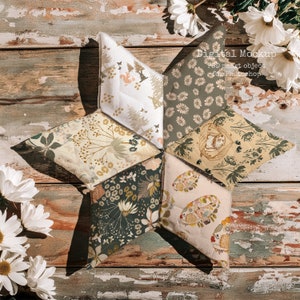 Peut inclure: Un arrangement en forme d'étoile de six carrés de tissu avec différents motifs floraux. Les carrés de tissu sont cousus ensemble pour créer une forme d'étoile. Les carrés de tissu sont tous de couleurs et de motifs différents. L'arrière-plan est une surface en bois rustique.