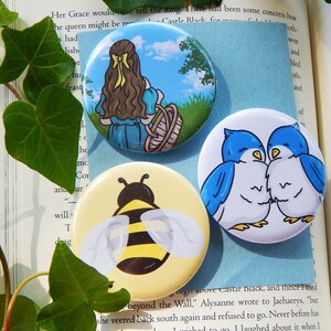 May include: Four round pinback buttons with different designs. The first button features a girl with long brown hair wearing a blue dress and holding a basket. The second button features a bee with yellow and black stripes. The third button features a blue bird with a white belly. The fourth button features two blue birds with white bellies.