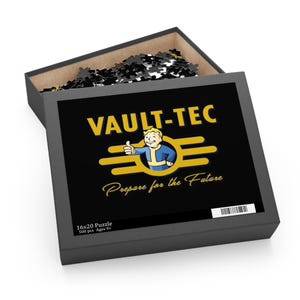 May include: A black puzzle box with the Vault-Tec logo in yellow and a cartoon character giving a thumbs up. The box is open, revealing black and white puzzle pieces. Text on the box reads "Prepare for the Future" and "16x20 Puzzle 500 pcs Ages 9+".
