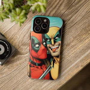 May include: A phone case featuring a colorful illustration of Deadpool and Wolverine. Deadpool is wearing his signature red and black suit, while Wolverine is wearing his yellow and blue costume. The case has a blue background and a camera cutout.