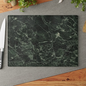 May include: A green marble chopping board with a dark green background and white veining. The board is rectangular and has a smooth surface.