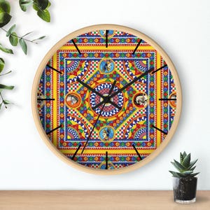 May include: A round wall clock with a colourful, intricate design featuring geometric patterns and figures. The clock face is yellow with red, blue, and green accents. The clock hands are black.