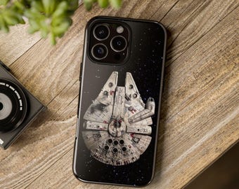 May include: A black smartphone case featuring a detailed graphic of the Millennium Falcon spaceship set against a dark, starry space background. The design shows the iconic circular hull, mechanical details, and thrusters of the spacecraft.