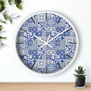 May include: White round clock with a blue and white patterned face. The pattern is made up of small squares and geometric shapes. The clock hands are black.