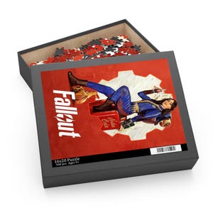 May include: A 16x20 inch puzzle box with the Fallout logo and artwork of a woman in a blue jumpsuit. The box is open, revealing puzzle pieces. The artwork is set against a red background with a white gear.
