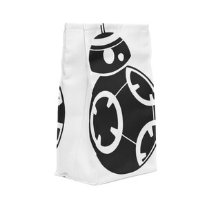 May include: White canvas tote bag featuring a black silhouette of a droid from Star Wars. The droid is round with a dome-shaped head and a single eye.