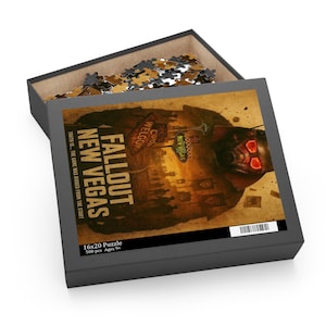 May include: A 16x20 inch puzzle box with the title "Fallout New Vegas" in bold letters. The box art features a desert scene with a character's face and the text "Truth is... The game was rigged from the start." The box contains 500 pieces.