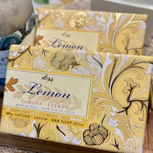 May include: Two lemon-scented bar soap boxes with yellow and gold floral designs. The boxes have the text "1894 Lemon" and "Made in Italy". Each bar soap weighs 10.5 oz.