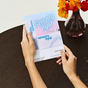 May include: A blue and pink brochure with the text "Seventy Hyal" and a client name section. The brochure is being held by a person's hands.