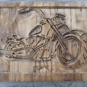 May include: A wooden wall art piece featuring a carved image of a motorcycle. The motorcycle is carved in detail, with visible wheels, handlebars, and engine.