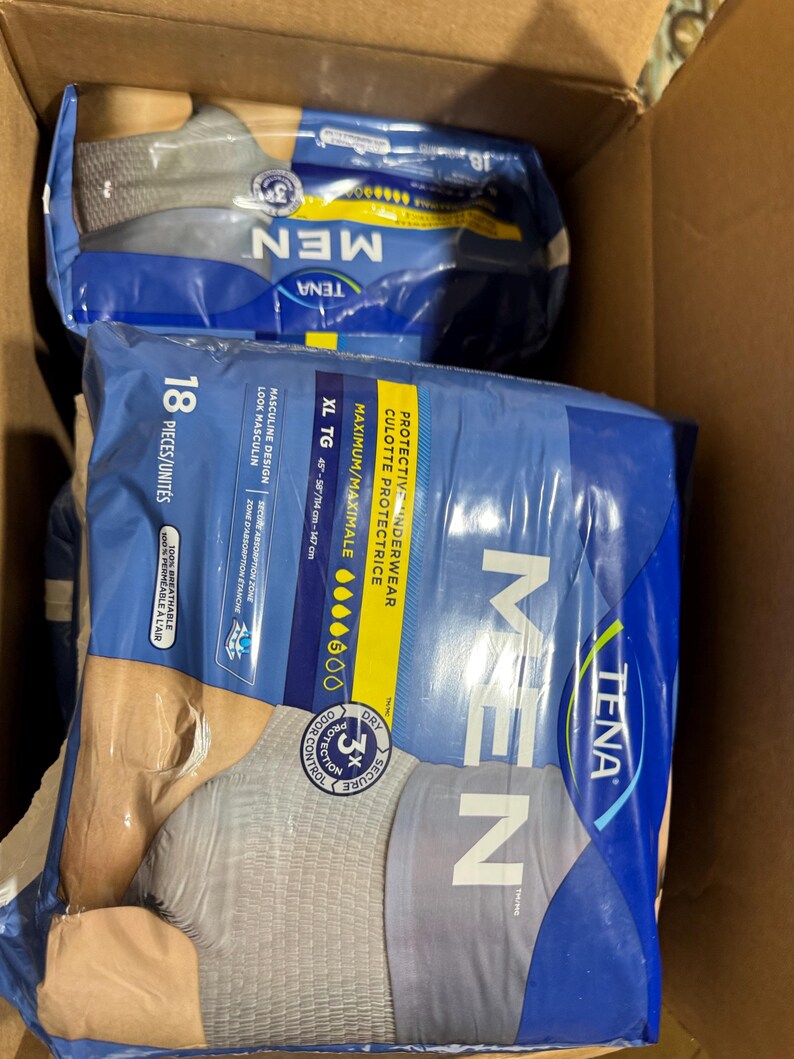 以下が含まれることがあります： 段ボール箱に入ったTENA男性用保護下着の2つのパッケージ。パッケージは青とグレーで、「MEN」の文字が大きく表示されています。パッケージにはXL TGと記載されており、ウエストサイズは114〜147cmです。